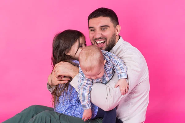 Otec s dětmi baví na růžovém pozadí — Stock fotografie