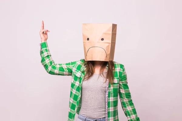 Femme malheureuse avec émoticône triste devant sac en papier sur sa tête sur fond blanc — Photo