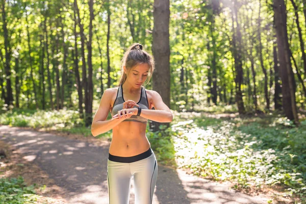 Menina ativa usando rastreador de fitness jogging relógio inteligente na natureza verão ao ar livre olhando para os dados de saúde durante a atividade esportiva — Fotografia de Stock