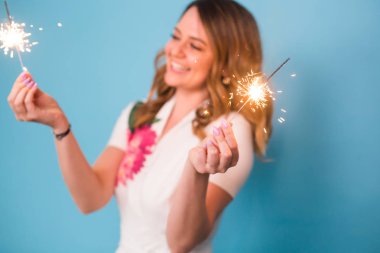 Genç mutlu kadın havai fişekleri ile kutlamak ve üzerinde mavi arka plan gül