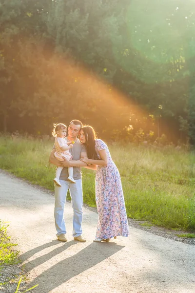 Feliz carrera mixta familia actividad al aire libre. Los padres y la hija del bebé se divierten y caminan en el parque de verano . — Foto de Stock