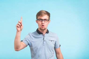 Vay canına, anlıyorum. Sürpriz genç erkek üzerinde mavi arka plan izole bir şey hatırlar gibi parmak yükseltir. Reaksiyon ve insanlar