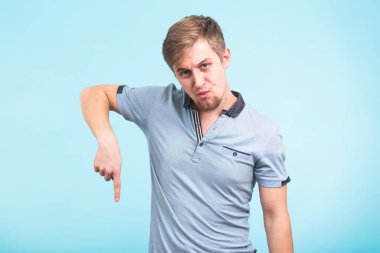 Reklam kavramı. Mavi zemin üzerine gülen gülümseme ile başarılı beyaz adam boş kopya alanı üzerinde onun parmaklarıyla işaret ediyor