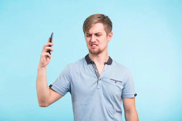 Bonito homem com um olhar cansado e irritado tira o telefone de sua orelha tentando se afastar das queixas de um povo obsessivo e irritante — Fotografia de Stock