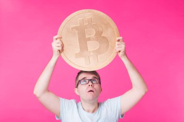 Büyük altın bitcoin, pembe arka plan tutan adam. Kripto para birimi, sanal para, internet ve ekonomi kavramı