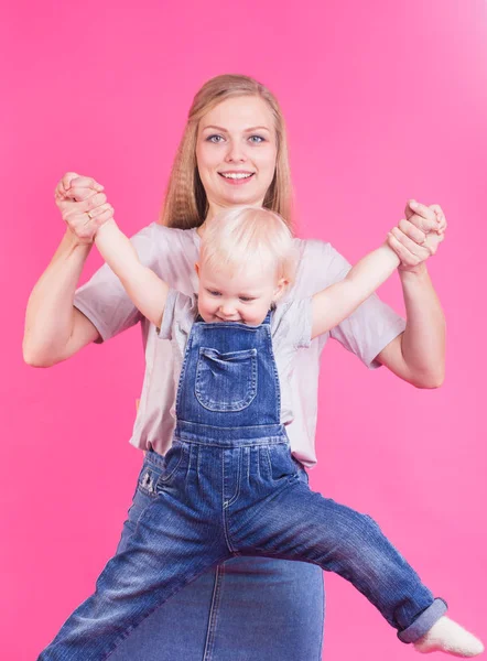 Glückliches kleines Mädchen und ihre Mutter haben Spaß auf rosa Hintergrund — Stockfoto