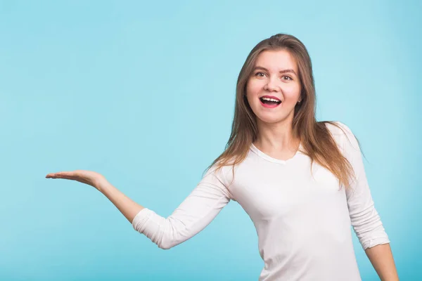 Mujer joven señalando espacio de copia sobre fondo azul — Foto de Stock