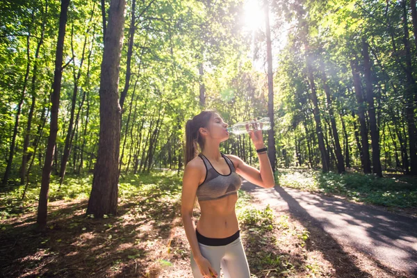 Mujer joven bebiendo agua después de correr al aire libre — Foto de Stock