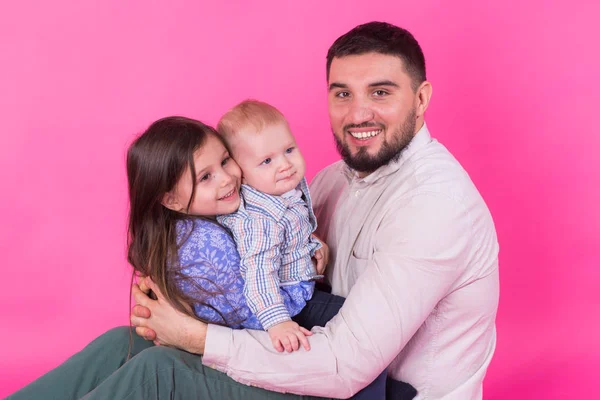 Schöner Vater mit seiner kleinen Tochter und seinem kleinen Sohn auf rosa Hintergrund — Stockfoto