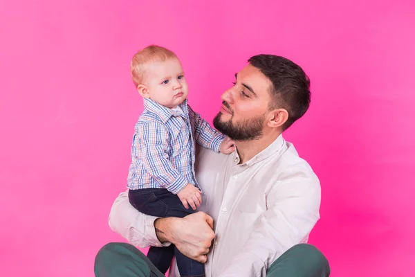 Padre feliz con su hijo bebé sobre fondo rosa — Foto de Stock