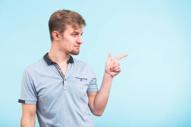 Reklam kavramı. Mavi zemin üzerine gülen gülümseme ile başarılı beyaz adam boş kopya alanı üzerinde onun parmaklarıyla işaret ediyor
