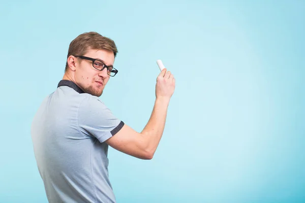 Estudo, estudantes, universidade e conceito de faculdade - Jovem homem engraçado detém giz isolado em fundo azul . — Fotografia de Stock