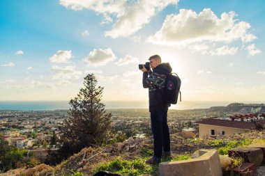 Deniz ve kayalar fotoğraflarını fotoğraf makinesi ile yapım sırt çantası ile genç fotoğrafçı. Akdeniz