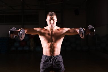 Spor salonunda spor yapan kaslı bir adam, pazularıyla egzersiz yapıyor. Güçlü erkek, çıplak karın kasları var..