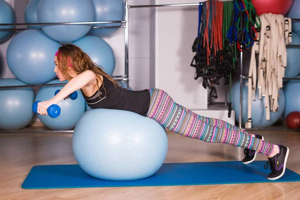 Mujer haciendo ejercicio con pesas en una pelota de fitness — Foto de Stock