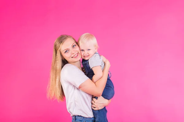 Jovem mãe e filha se divertindo juntos no fundo rosa — Fotografia de Stock