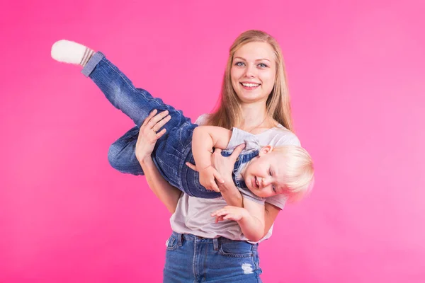 Lykkelig lille pige og hendes mor har det sjovt over lyserød baggrund - Stock-foto