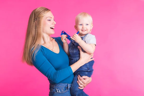 Familia divertida sobre fondo rosa. Madre y su hija. Mamá y el niño se están divirtiendo . — Foto de Stock