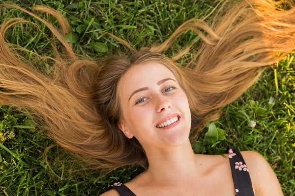 Top view of a happy relaxed woman lying on the green grass and smiling. — Stock Photo, Image