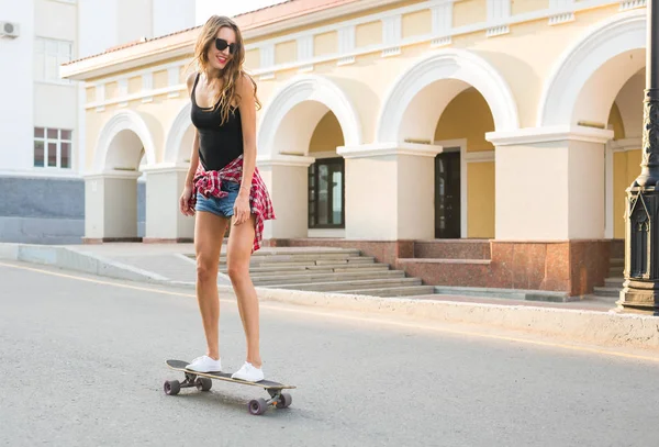 Mooie jonge hipster vrouw met skateboard buitenshuis — Stockfoto