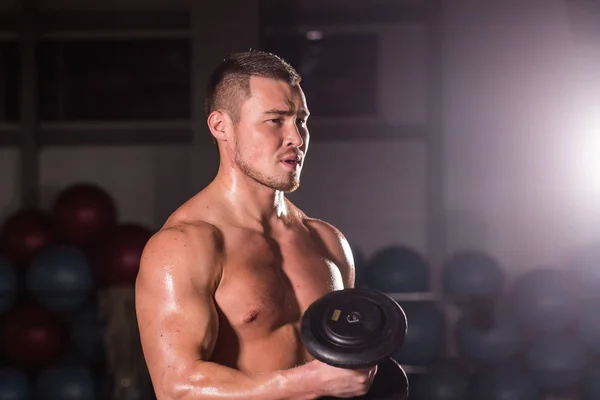 Muskulöser Mann trainiert im Fitnessstudio und macht Übungen mit Kurzhanteln am Bizeps, kräftiger männlicher nackter Oberkörper. — Stockfoto