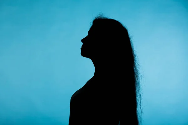 Retrato de una mujer joven mirando hacia arriba silueta horizontal sobre fondo azul —  Fotos de Stock
