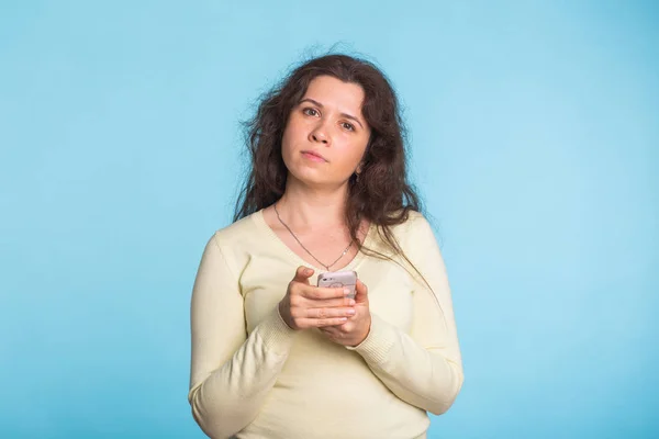 Jovem mulher sorrindo usando telefone celular contra fundo azul — Fotografia de Stock