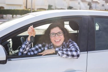 Genç kadın test sürücü yeni araba ve gösteren anahtar. Araba satın alma veya kiralama kavramı