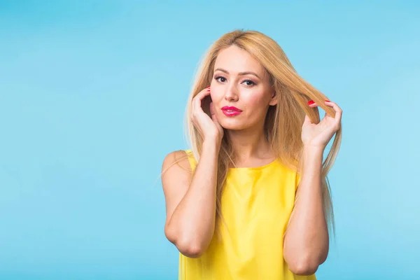 Portret van gelukkig vrolijk lachende jonge mooie blonde vrouw op blauwe achtergrond — Stockfoto