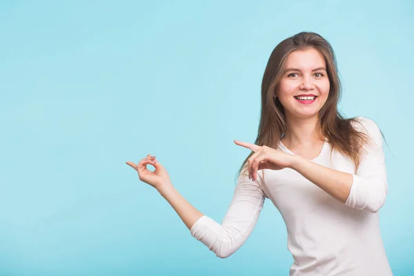 Mujer joven señalando espacio de copia sobre fondo azul — Foto de Stock