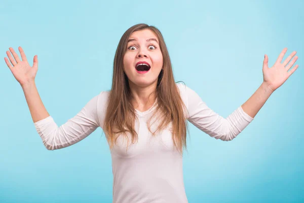 Sorprendida joven gritando sobre fondo azul. Mirando la cámara — Foto de Stock