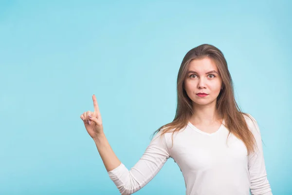 Mujer joven señalando espacio de copia sobre fondo azul — Foto de Stock