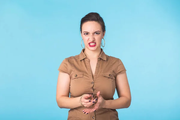 Donna aggressiva arrabbiata con espressione feroce su sfondo blu — Foto Stock