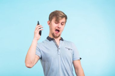 Portre kızgın genç adam, adam deli öğrenci telefon üzerinde mavi arka plan üzerinde bağırarak kapatın. Negatif insan duygu yüz ifade duygu tutum