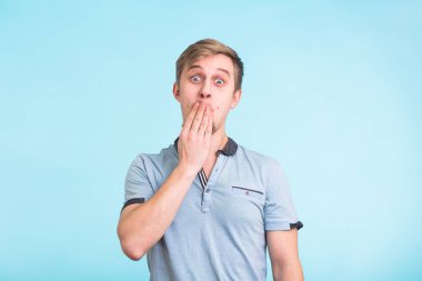 Genç adam ağzını mavi arka plan üzerinde el ile kapsayan portresi