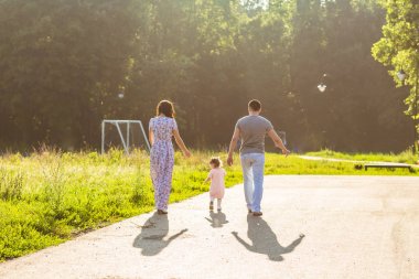 Mutlu aile açık hava etkinliği. Anne ve bebek kızı eğleniyor ve yaz Park'ta yürüyordunuz arkadan görünüş.