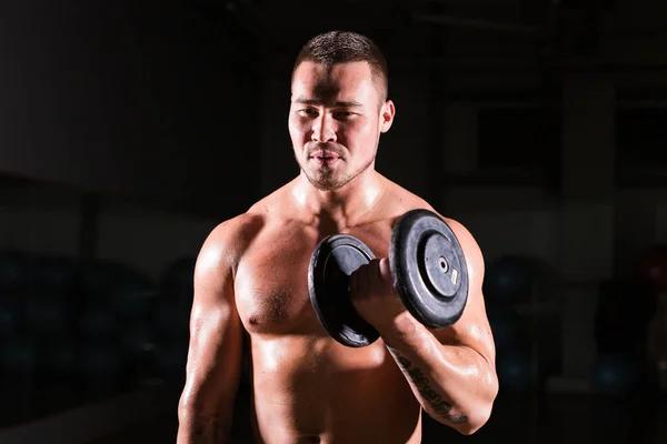 Svalnatý muž cvičení v tělocvičně s činky na biceps, silné mužské nahý trup abs. — Stock fotografie