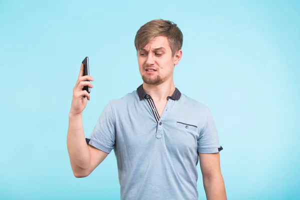 Bonito homem com um olhar cansado e irritado tira o telefone de sua orelha tentando se afastar das queixas de um povo obsessivo e irritante — Fotografia de Stock