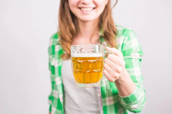 Primer plano de la joven mujer sosteniendo una taza de cerveza llena de cerveza y sonriendo sobre fondo blanco — Foto de Stock
