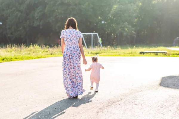 Matka i córka na świeżym powietrzu. Widok z tyłu z Mama i dziecko córka zabawy i spacery w parku lato. — Zdjęcie stockowe