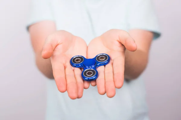 Mano maschile tenendo popolare fidget spinner giocattolo su sfondo bianco, giocattolo di sollievo dall'ansia, anti stress e relax fidgets — Foto Stock