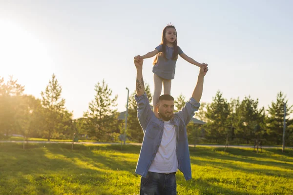 Homem feliz segurando sua filhinha no pescoço no parque de verão — Fotografia de Stock