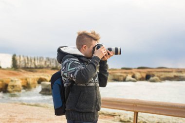 Deniz ve kayalar fotoğraflarını fotoğraf makinesi ile yapım sırt çantası ile genç fotoğrafçı. Akdeniz
