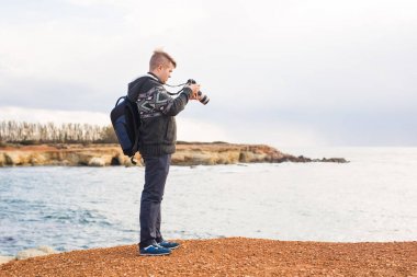 Deniz ve kayalar fotoğraflarını fotoğraf makinesi ile yapım sırt çantası ile genç fotoğrafçı. Akdeniz