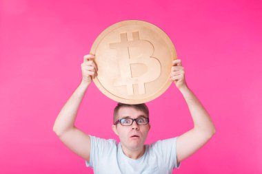 Büyük altın bitcoin, pembe arka plan tutan adam. Kripto para birimi, sanal para, internet ve ekonomi kavramı