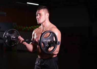 Spor salonunda spor yapan kaslı bir adam, pazularıyla egzersiz yapıyor. Güçlü erkek, çıplak karın kasları var..