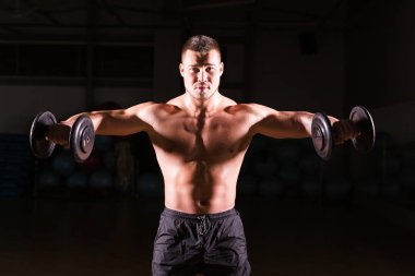 Spor salonunda spor yapan kaslı bir adam, pazularıyla egzersiz yapıyor. Güçlü erkek, çıplak karın kasları var..