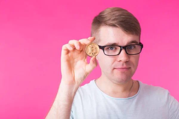 Hombre sosteniendo bitcoin sobre fondo rosa. Cripto moneda, dinero virtual, internet y concepto de economía — Foto de Stock