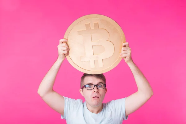 Hombre sosteniendo bitcoin grande de oro sobre fondo rosa. Cripto moneda, dinero virtual, internet y concepto de economía — Foto de Stock