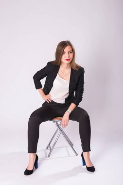 Beyaz arka plan üzerinde sandalye üzerinde oturan güzel cinsel işkadını.